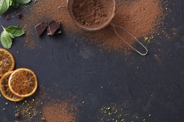 Sifted cocoa powder in a sieve over black background clipart
