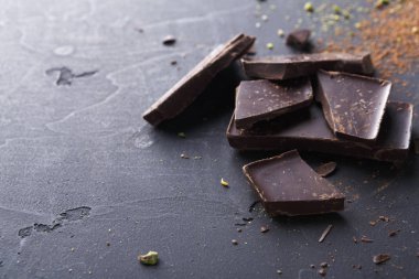 Koyu çikolata parçaları ve siyah arka plan üzerine kakao tozu