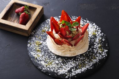 Siyah arka plan üzerine çilek ile lezzetli Anna Pavlova beze pasta