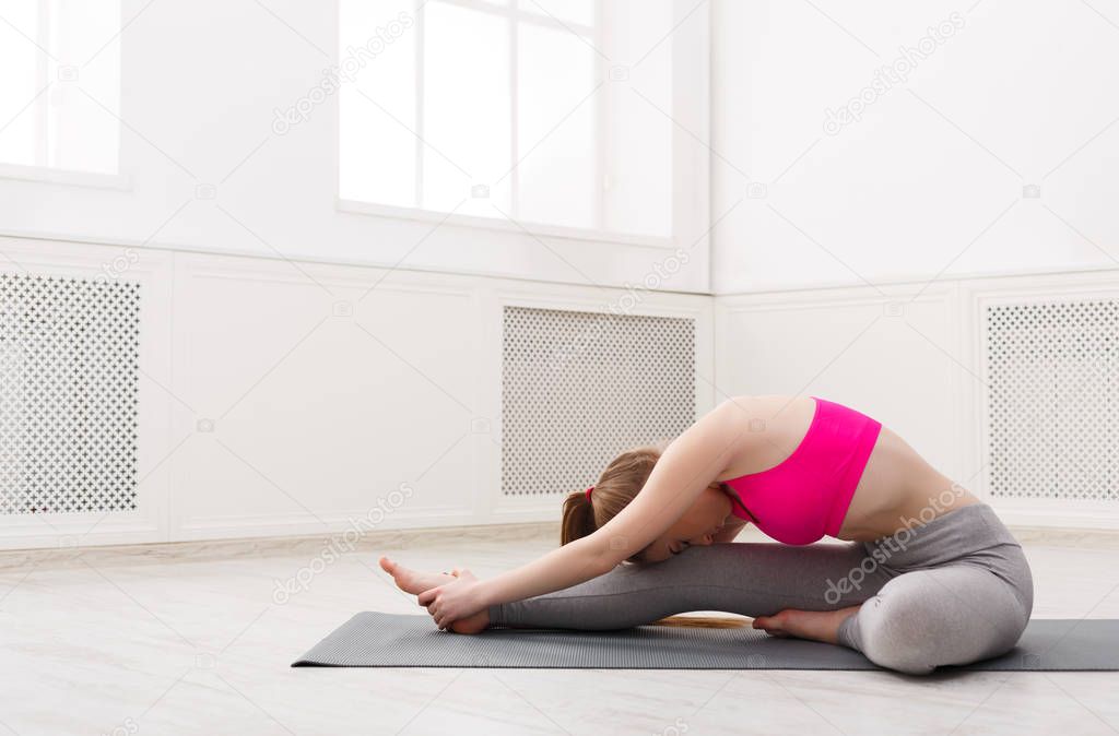 Woman training yoga in seated head to knee pose.