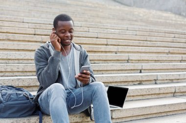 Merdivenlerde oturan ve smartphone kullanarak öğrenci