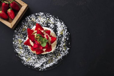 Siyah arka plan üzerine çilek ile lezzetli Anna Pavlova beze pasta