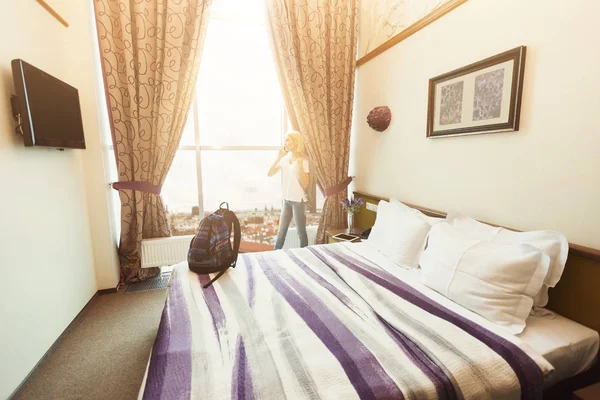 Woman standing near window in hotel room — Stock Photo, Image