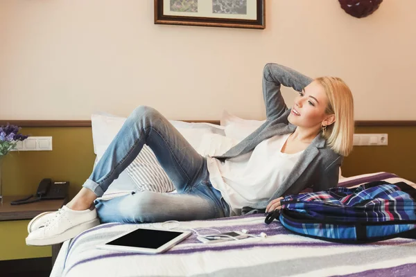 Fiatal nő ágyon szállodai szobában — Stock Fotó