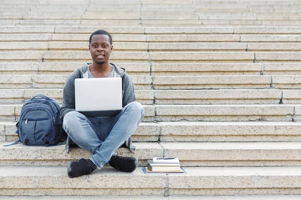 Estudiante sonriente sentado en escaleras usando laptop — Foto de Stock