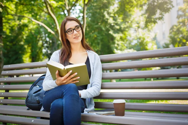Młoda kobieta azjatyckich w okularach, siedząc na ławce w parku. Relaks i czytanie książek — Zdjęcie stockowe