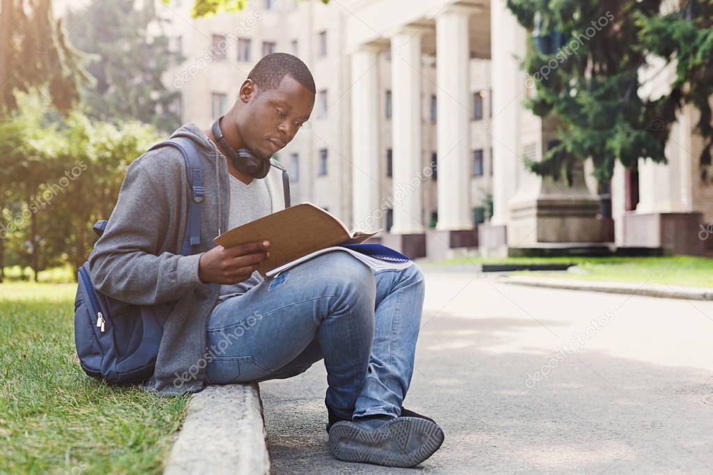 Young man reading notes at university copy space