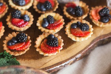 Ahşap kesme tahtası üzerinde çilek ile küçük tartalettes
