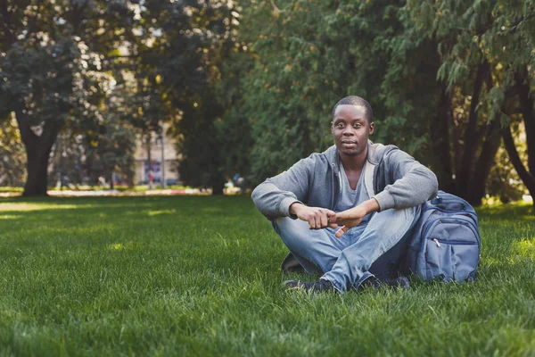 Joven hombre guapo sentado en la hierba al aire libre —  Fotos de Stock