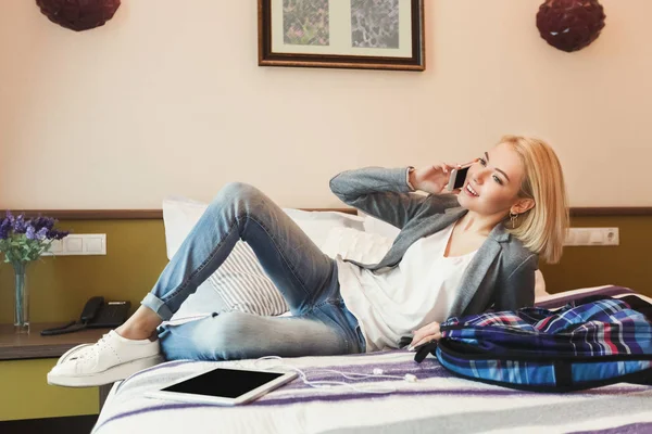 Счастливая женщина лежит на кровати в номере отеля — стоковое фото