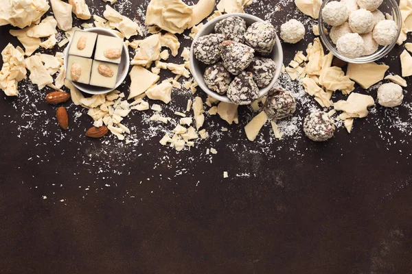 Zerkleinerte weiße Schokoladenstücke und Trüffel auf dunklem Hintergrund — Stockfoto