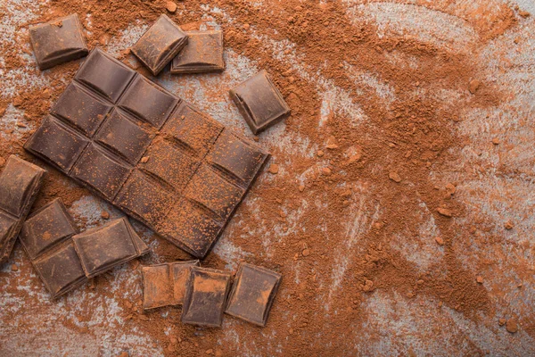 Krossad choklad bitar och kakao på grå bakgrund — Stockfoto