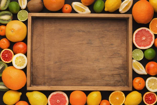 Haufen Zitrusfrüchte und Saftglas auf Holztablett, Draufsicht — Stockfoto