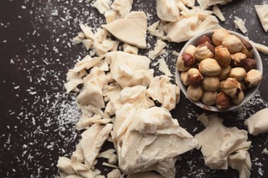 Ezilmiş beyaz çikolata parçaları ve gri arka plan üzerinde fındık