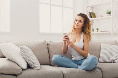 Kanepenin üzerinde cep telefonu kullanan genç kız