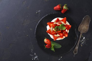 Siyah arka plan üzerine çilek ile lezzetli Anna Pavlova beze pasta