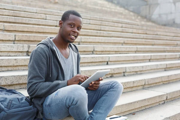 Lächelnder Student sitzt mit Tablet auf Treppe — Stockfoto