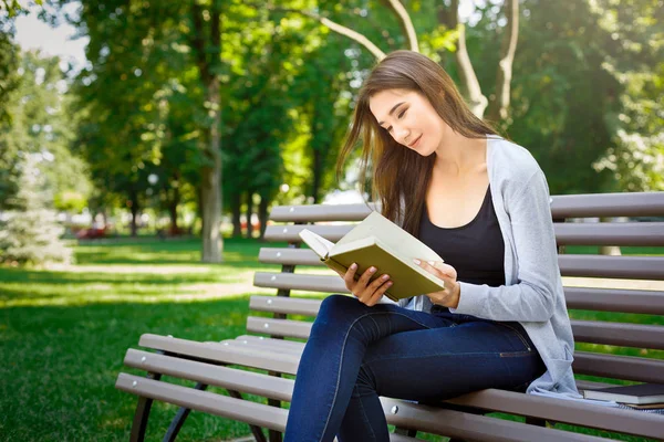 Genç Asyalı kadın parkta bir bankta oturmuş. Rahatlatıcı ve bir kitap okuma — Stok fotoğraf