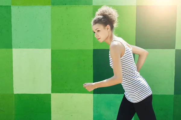 Side view of woman running against bright wall — Stock Photo, Image