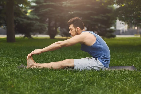 Fitness man stretching on grass outdoors — Stock Photo, Image