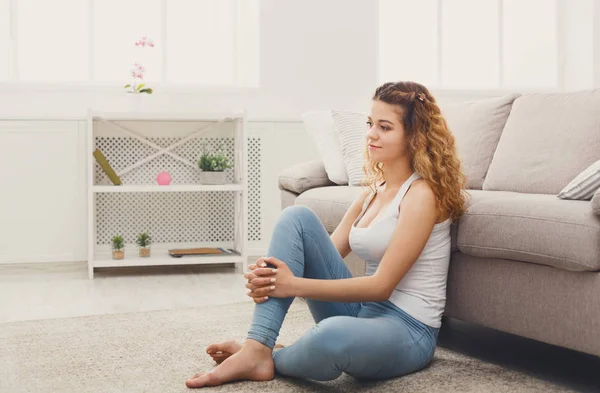 Young redhead woman thinking on beige couch — Stock Photo, Image