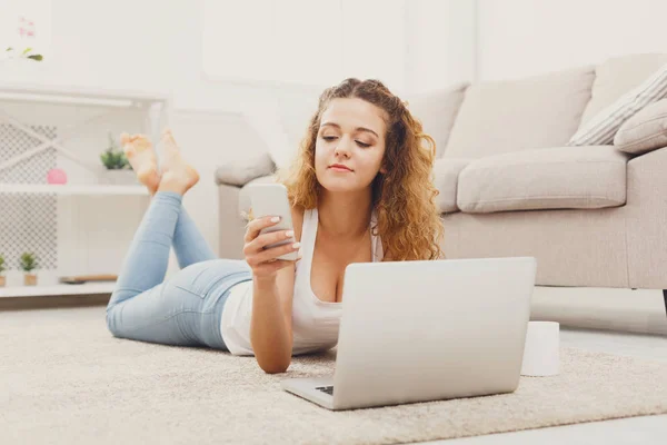 Chica estudiante sonriente utilizando el ordenador portátil y teléfono inteligente — Foto de Stock