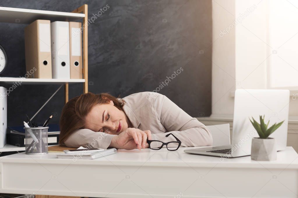 Tired business woman sleeping on workplace in office