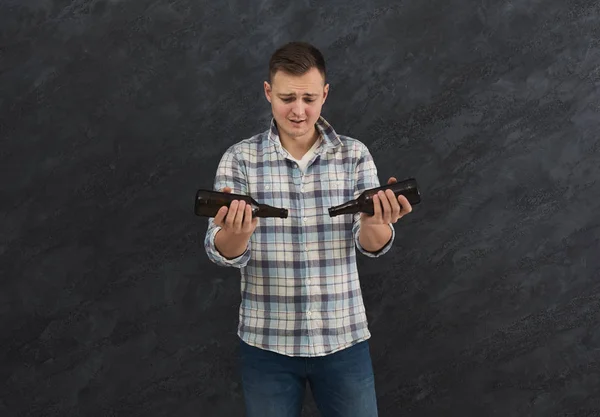 stock image Young guy with headache holding bottle of beer