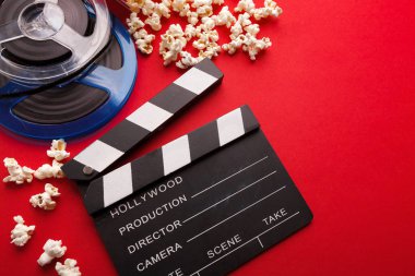 Klaket, film makaraları ve kırmızı bir arka plan üzerinde patlamış mısır