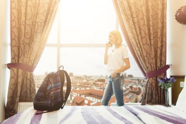Otel odasında pencere yanında duran kadın