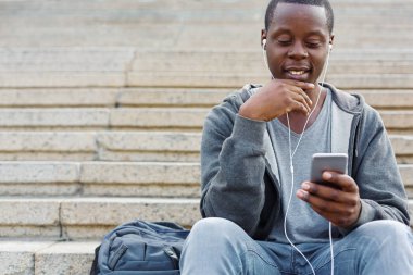 Merdivenlerde oturan ve smartphone kullanarak öğrenci