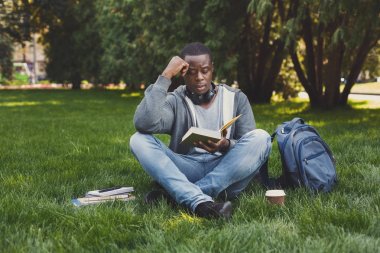 Genç adam park kopya alanı içinde kitap okumak