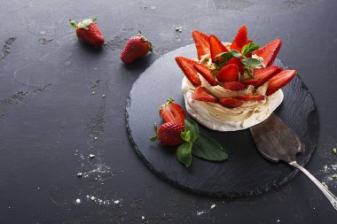 Siyah arka plan üzerine çilek ile lezzetli Anna Pavlova beze pasta