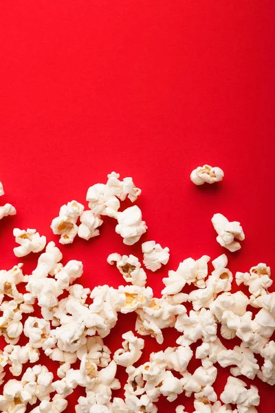 Slaty popcorn scattered on red background, top view — Stock Photo, Image