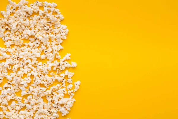 Slaty popcorn scattered on yellow background, top view — Stock Photo, Image