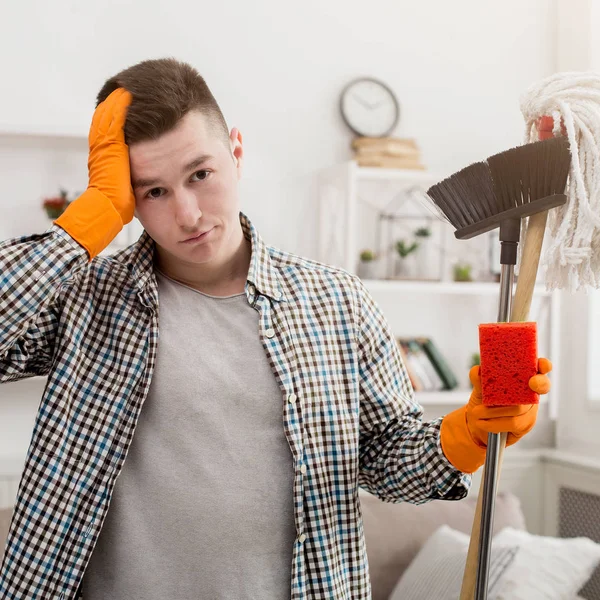 Giovane uomo stanco pulizia casa, spazzare — Foto Stock