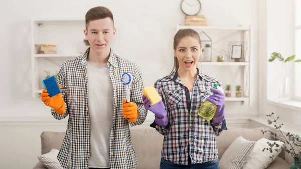 Jovem casal segurando equipamentos de limpeza em casa — Fotografia de Stock