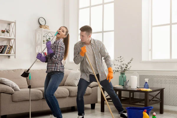 Молода пара прибирає будинок, розважається — стокове фото