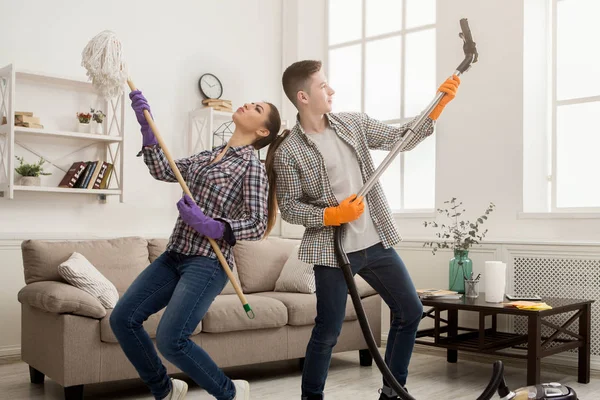 Молода пара прибирає будинок, розважається — стокове фото