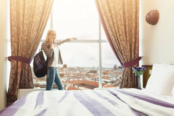 Mujer de pie cerca de la ventana en la habitación del hotel —  Fotos de Stock