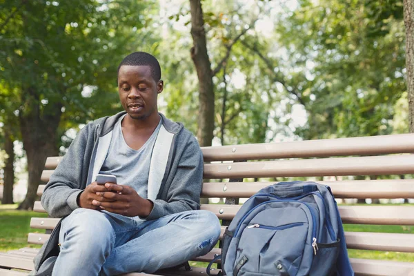 Szép ember ül, és használ smartphone szabadban — Stock Fotó