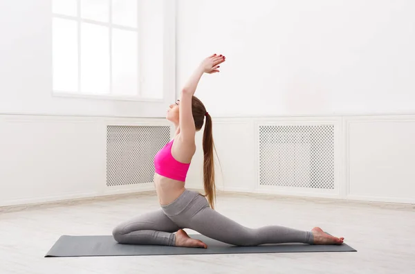 Kvinnan utbildning yoga i kung pigeon pose. — Stockfoto