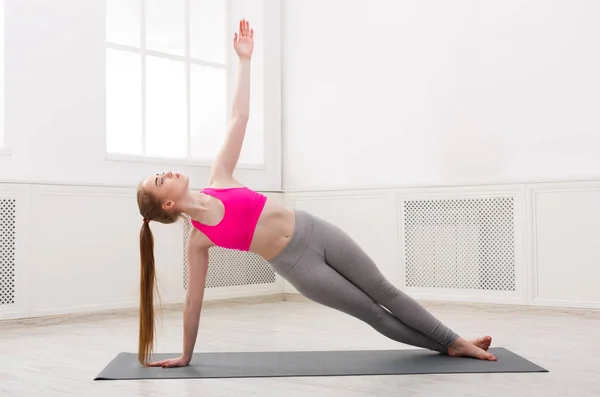 Mujer entrenando yoga en pose de tablón lateral — Foto de Stock
