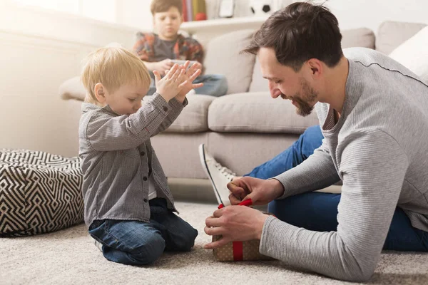 Pai dá seu filho presente em caixa vermelha em casa — Fotografia de Stock