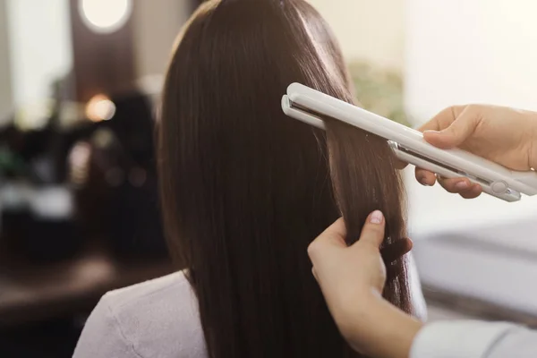 Endireitamento de cabelo por um cabeleireiro em um salão de beleza profissional , — Fotografia de Stock