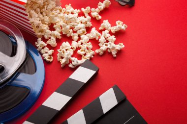 Klaket, film makaraları ve kırmızı bir arka plan üzerinde patlamış mısır