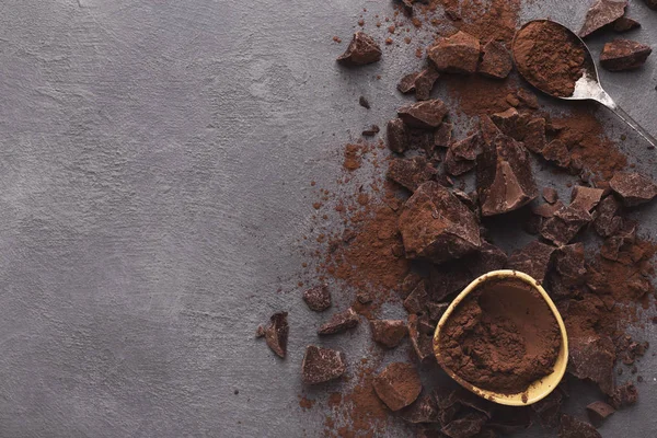 Gemalen chocolade stukken op de grijze achtergrond, bovenaanzicht — Stockfoto