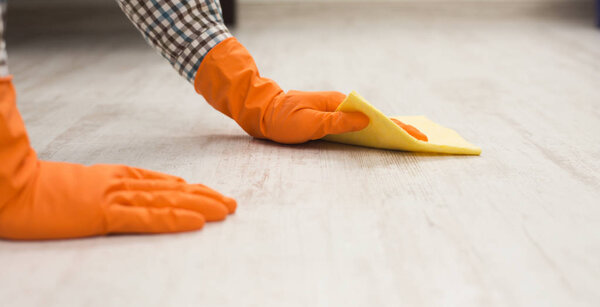 Неузнаваемый мужчина моет пол тряпкой
