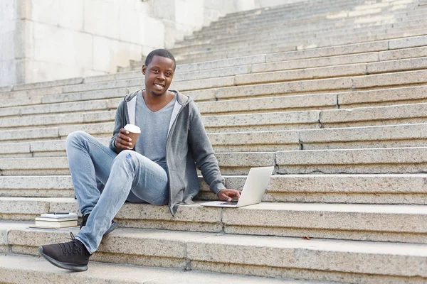 Estudiante sonriente sentado en escaleras usando laptop — Foto de Stock