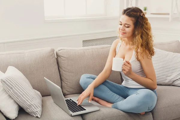 Menina com laptop sentado no sofá bege — Fotografia de Stock